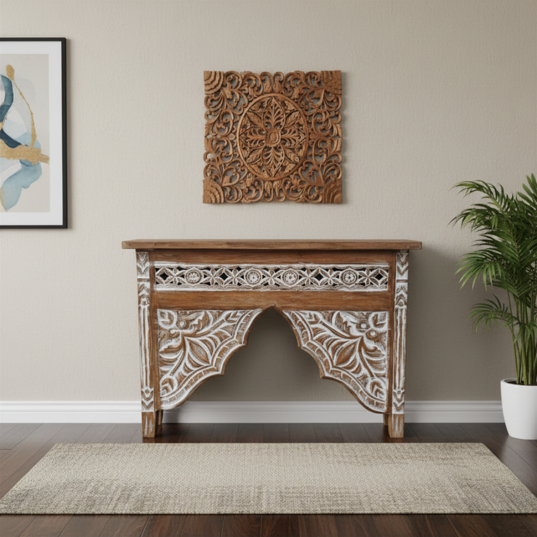 Decorative wooden console table with intricate carvings in a room with a plant and framed artwork.
