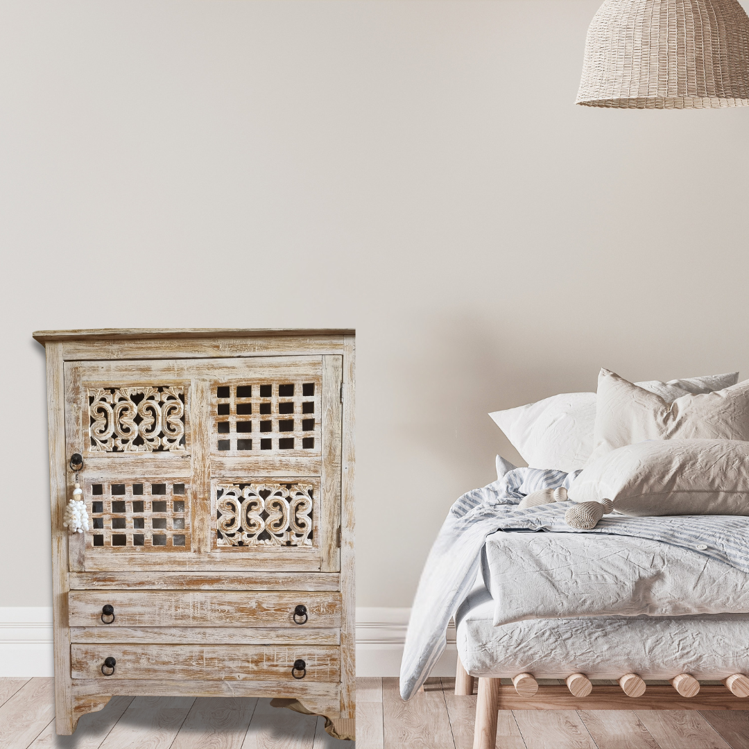 A rustic reclaimed teak wood cabinet with intricate carvings, featuring a white-wash finish and traditional hardware.