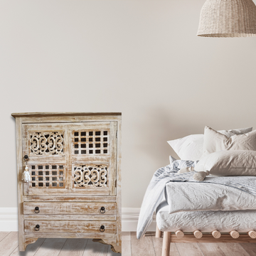 A rustic reclaimed teak wood cabinet with intricate carvings, featuring a white-wash finish and traditional hardware.