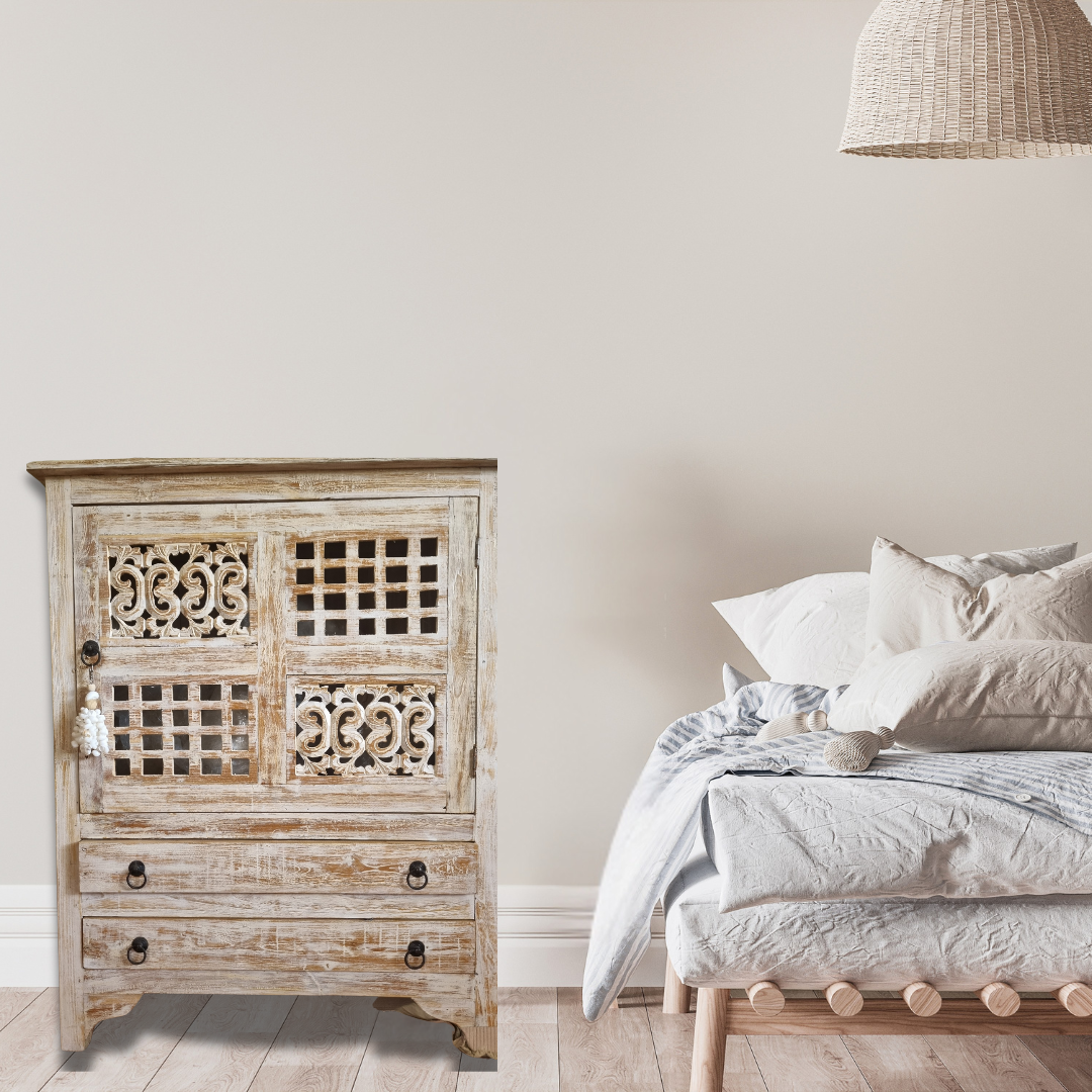 A rustic reclaimed teak wood cabinet with intricate carvings, featuring a white-wash finish and traditional hardware.