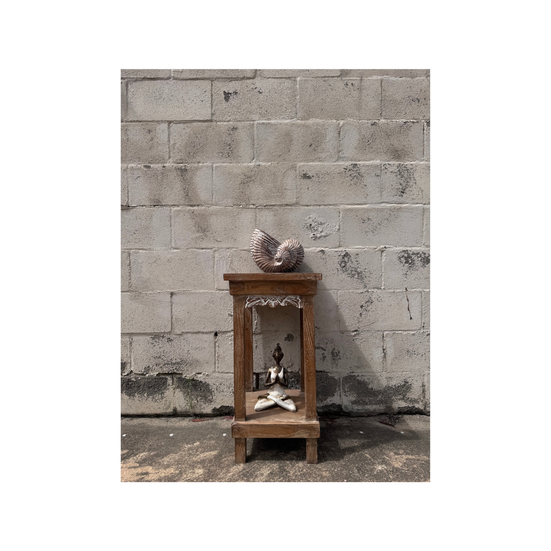 Small wooden shrine with decorative items against a textured stone wall.