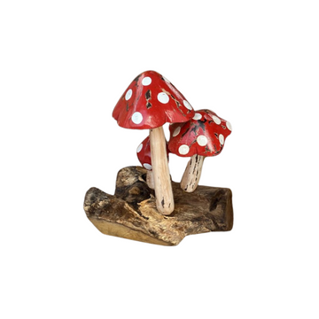 Three spotted caps with distressed paint and pale stems on a broad, irregular timber base against a white background