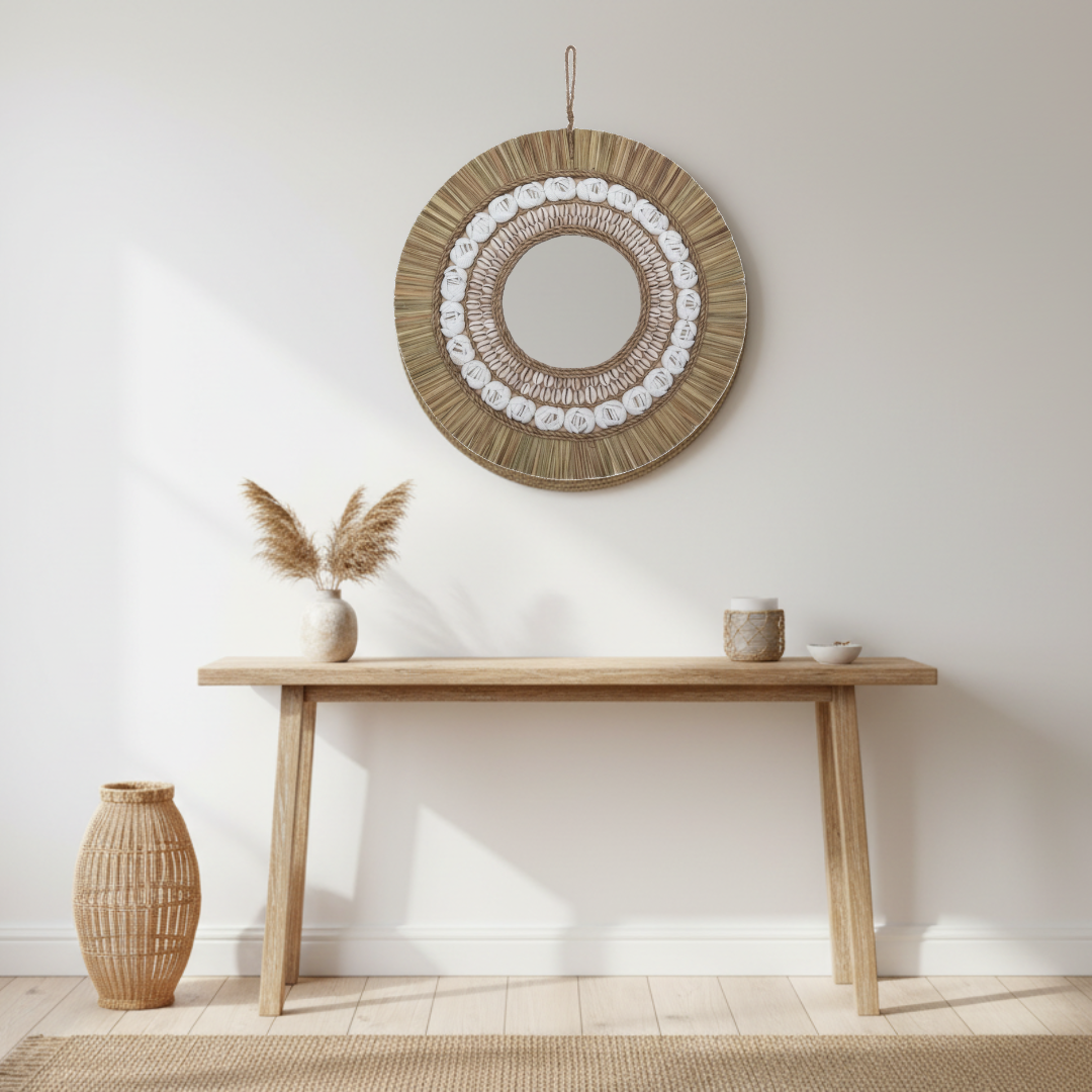 Natural tone boho coastal wall mirror with raffia fringe and cowrie shell detail, styled above a timber console table with pampas grass and rattan vase in a bright coastal hallway — 40x40cm — handcrafted coastal boho home decor by Azure Decor