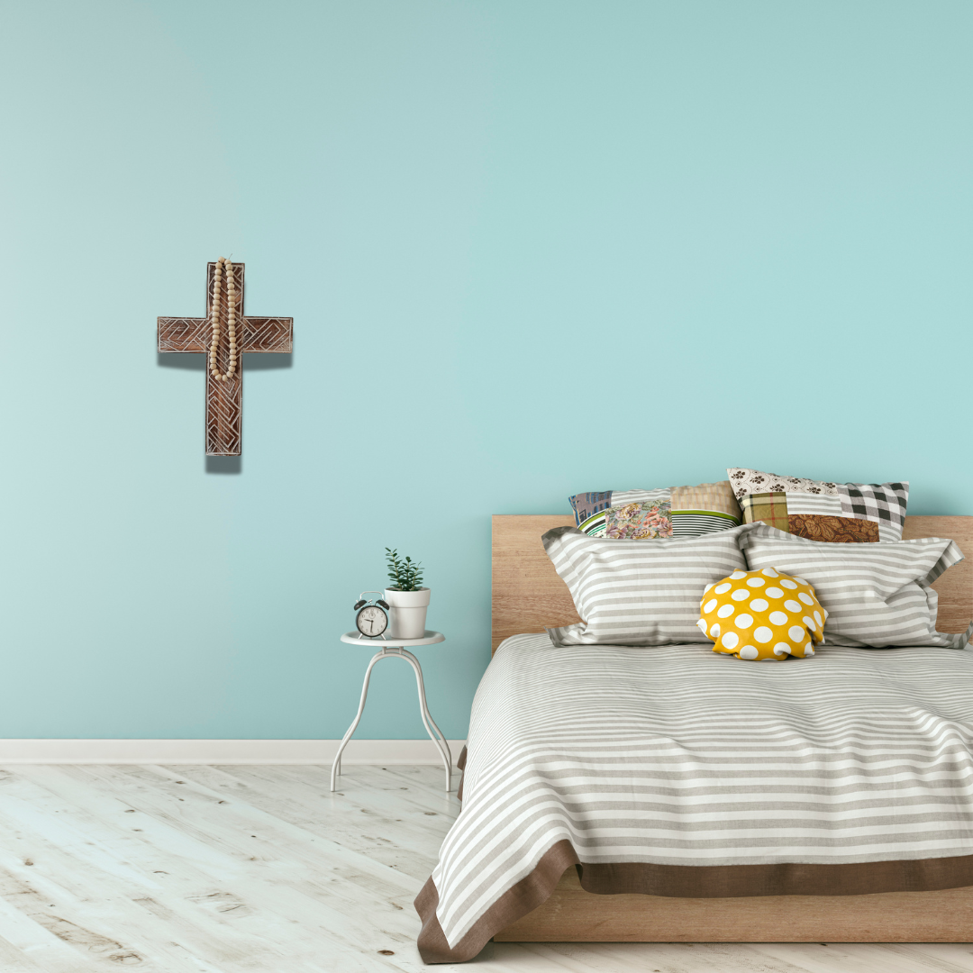 Bedroom with wooden bed, striped bedding, and decorative pillows against a light blue wall.