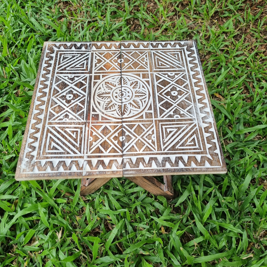 Small rustic boho foldable wooden picnic table with hand carved geometric tribal pattern and natural white wash finish, top-down view on green grass — Boho Tribal Square design 30cm x 30cm by Azure Decor