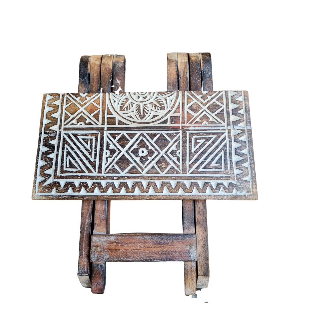 Small rustic boho foldable wooden picnic table with hand carved geometric tribal pattern and brown wash finish, folding cross legs, on white background