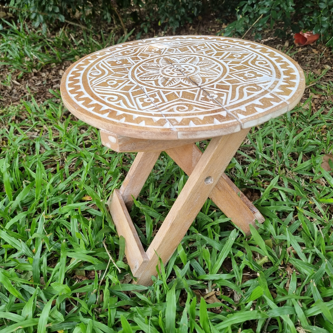 Small rustic boho foldable wooden picnic table with hand carved mandala tribal pattern and natural white wash finish, folding cross legs, styled outdoors on green grass — Boho Tribal Round design 30cm x 30cm by Azure Decor
