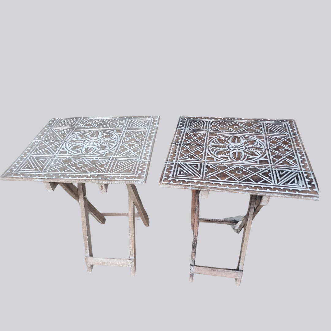 Two rustic boho foldable wooden side tables side by side showing Boho Natural Wash and Boho Brown Wash finishes, both with hand carved geometric tribal pattern, folding cross legs, on grey background — 40cm x 40cm x 50cm by Azure Decor