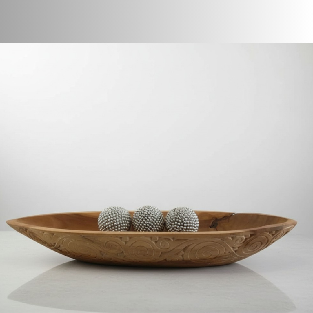 Wooden bowl with decorative patterns containing three silver textured balls on a white background