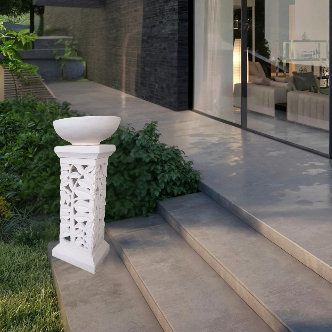 Decorative white column with bowl on a patio area with modern house in the background