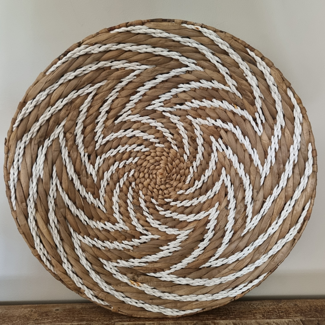 Round woven mat with brown and white pattern on a wooden surface