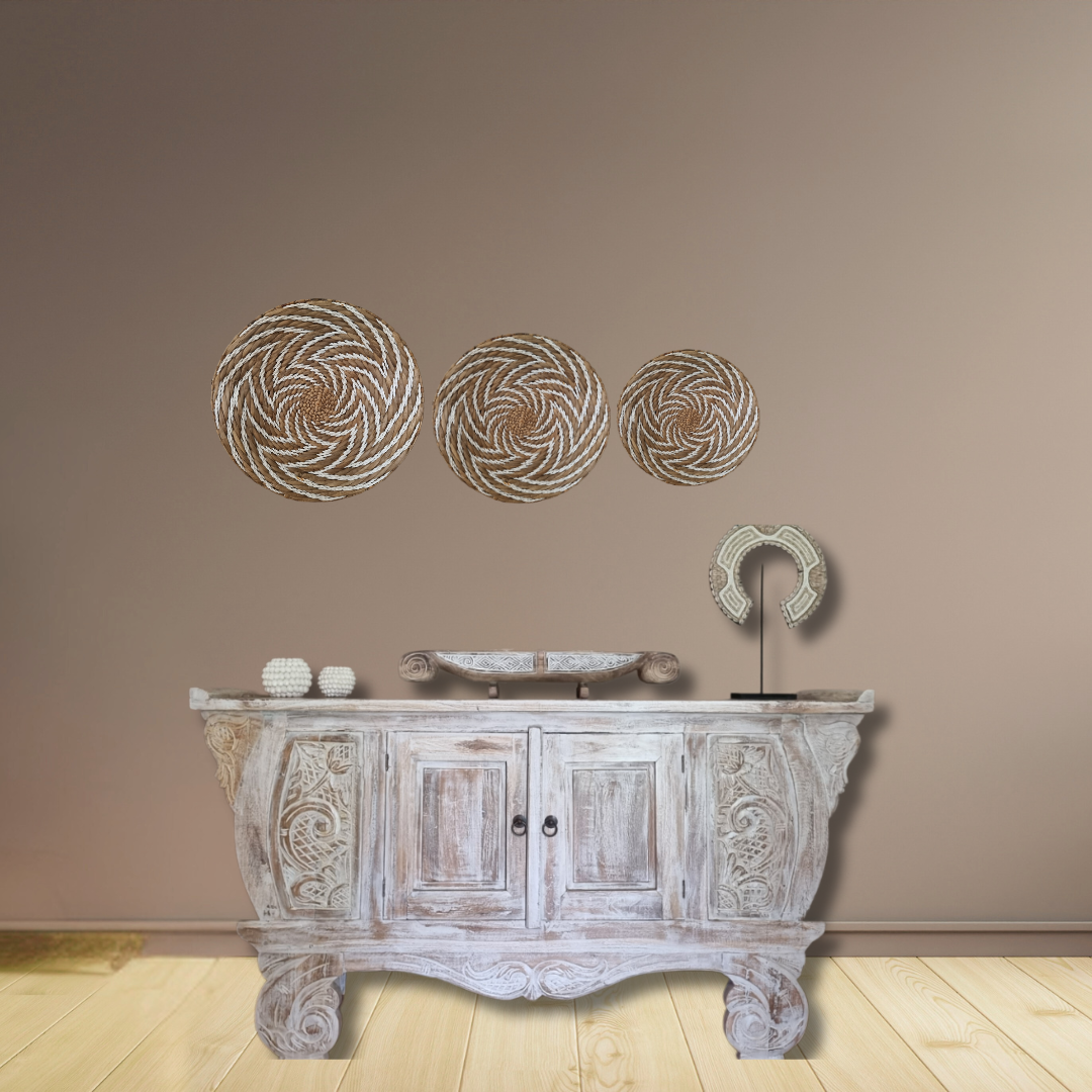 Decorative wall art above a wooden cabinet with a decorative faucet on a beige wall.