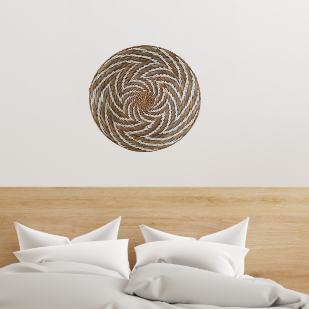 Round woven wall art above a bed with white bedding