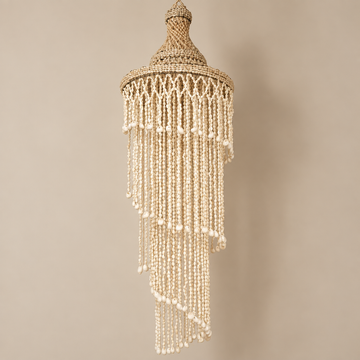 Warm cream shell strands cascading from a woven top against a plain beige background