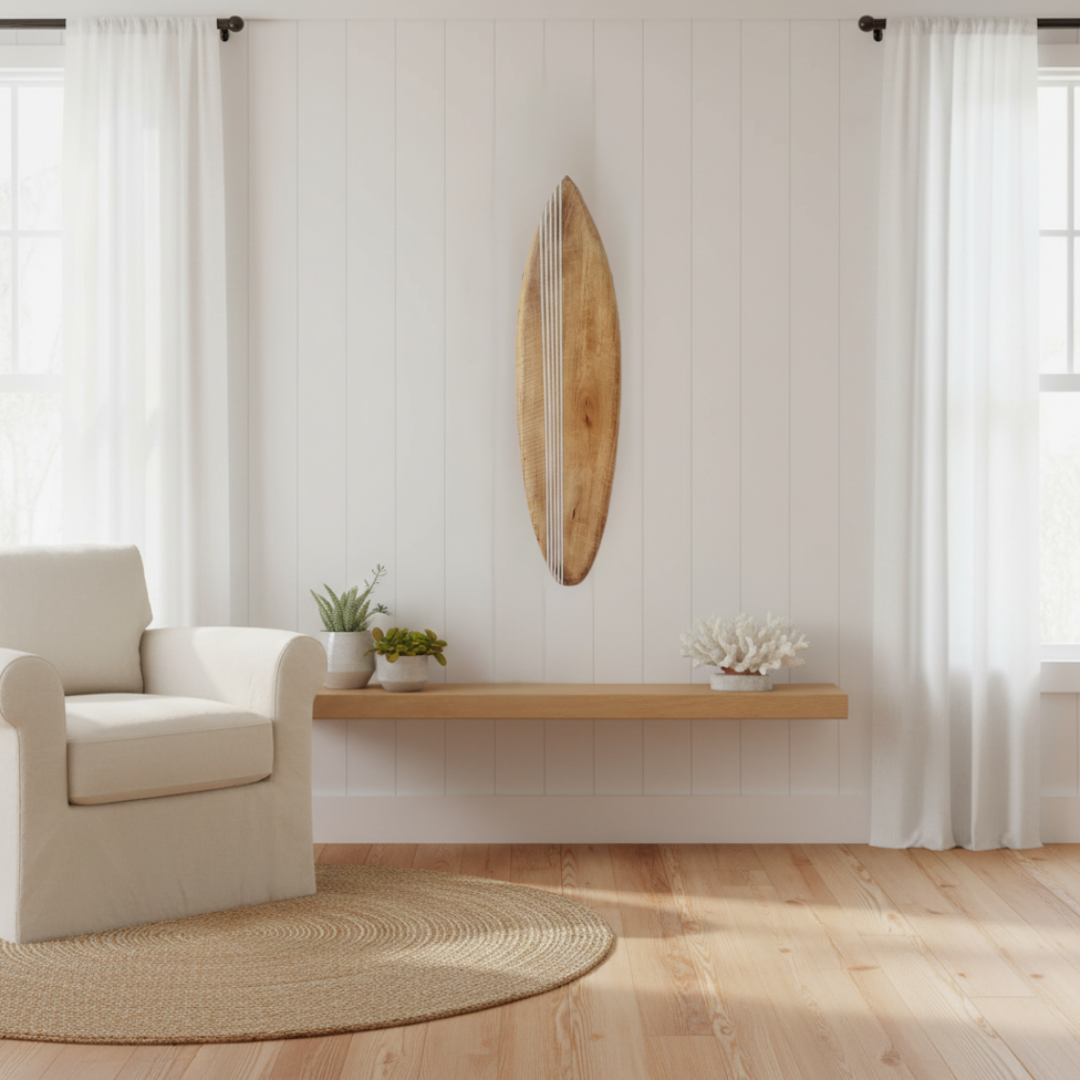 Natural timber board mounted on a blue-grey wall above a white low-profile TV unit, pampas grass in a white vase, beach photography prints on the right