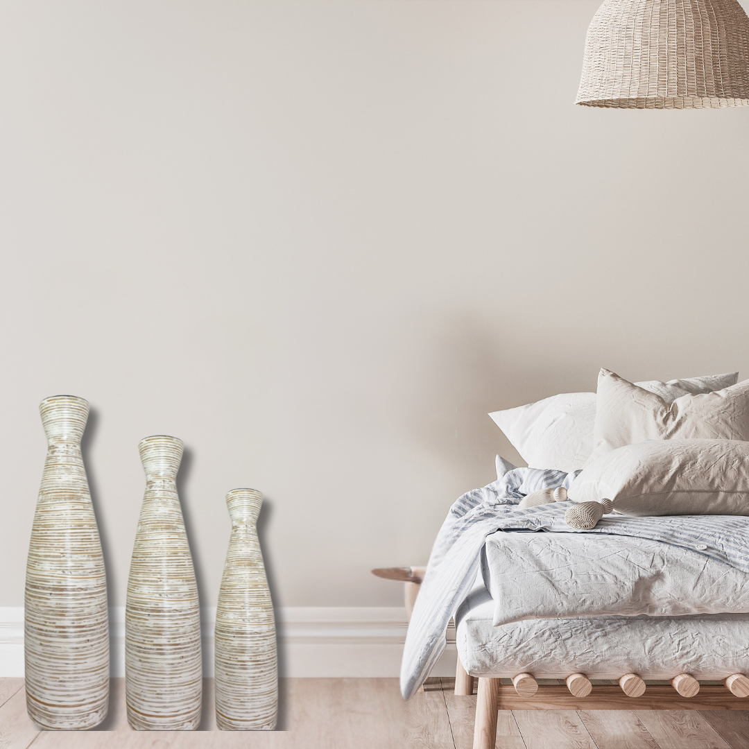 Set of three decorative vases in a bedroom setting with a bed and lamp.