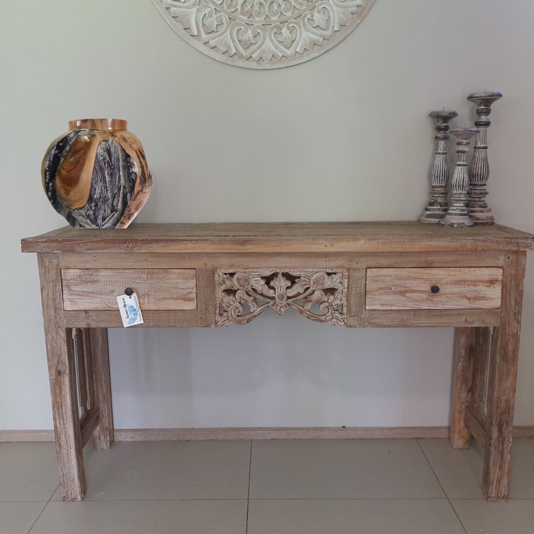 Wooden console table with decorative carvings against a plain wall.