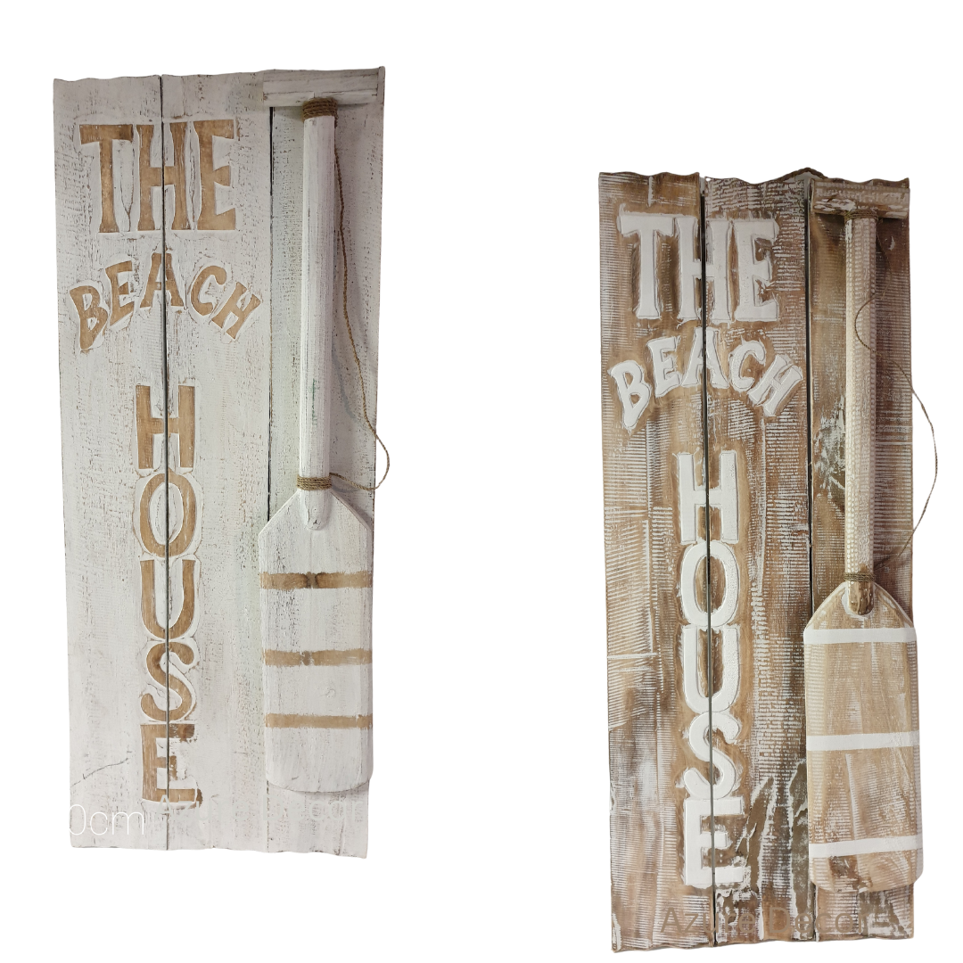 Two wooden signs with the text 'THE BEACH HOUSE' printed on them, one in natural wood color and one painted white, each with a decorative wooden paddle attached to the side.