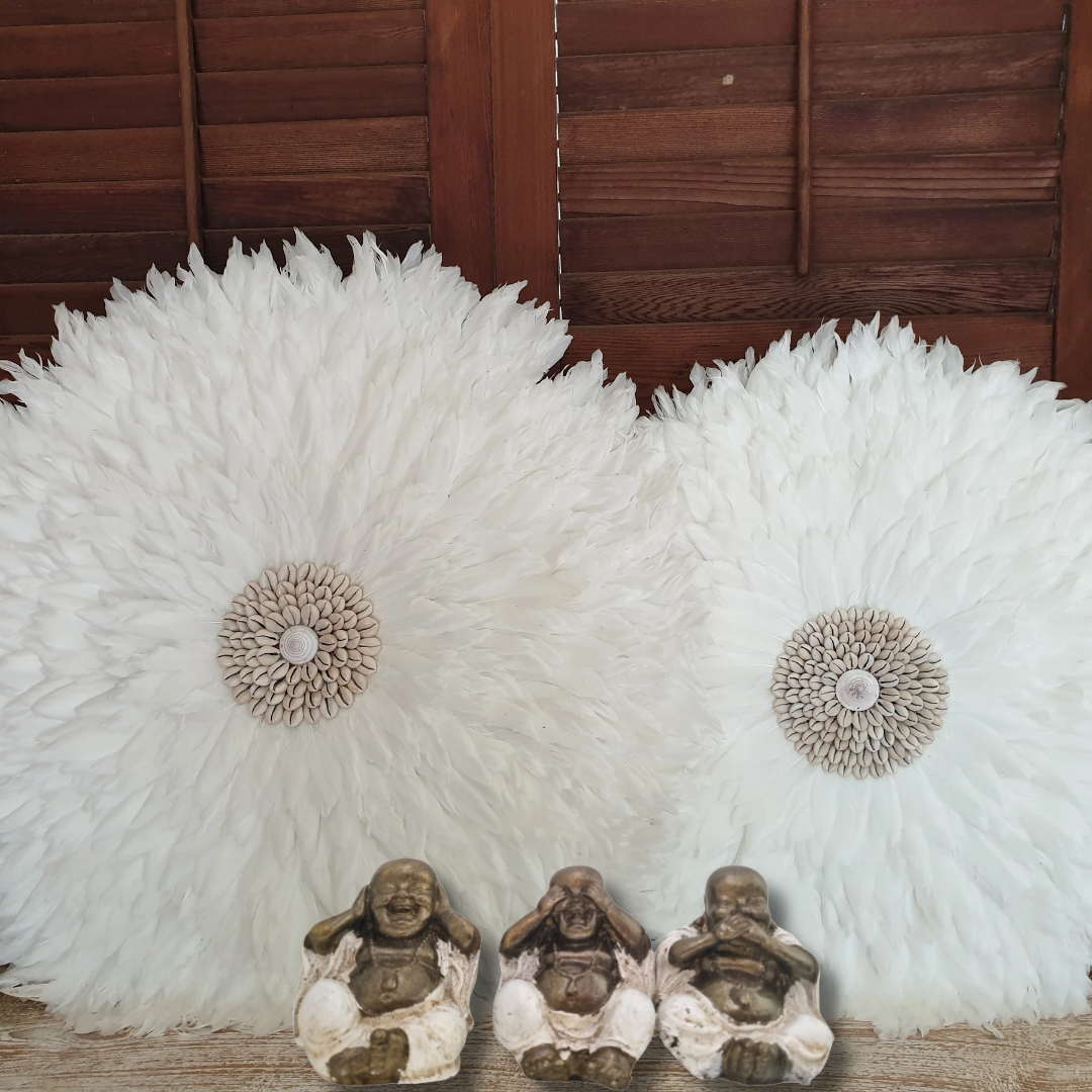 Decorative wall art with white feather-like patterns and small figurines in front of a wooden panel.