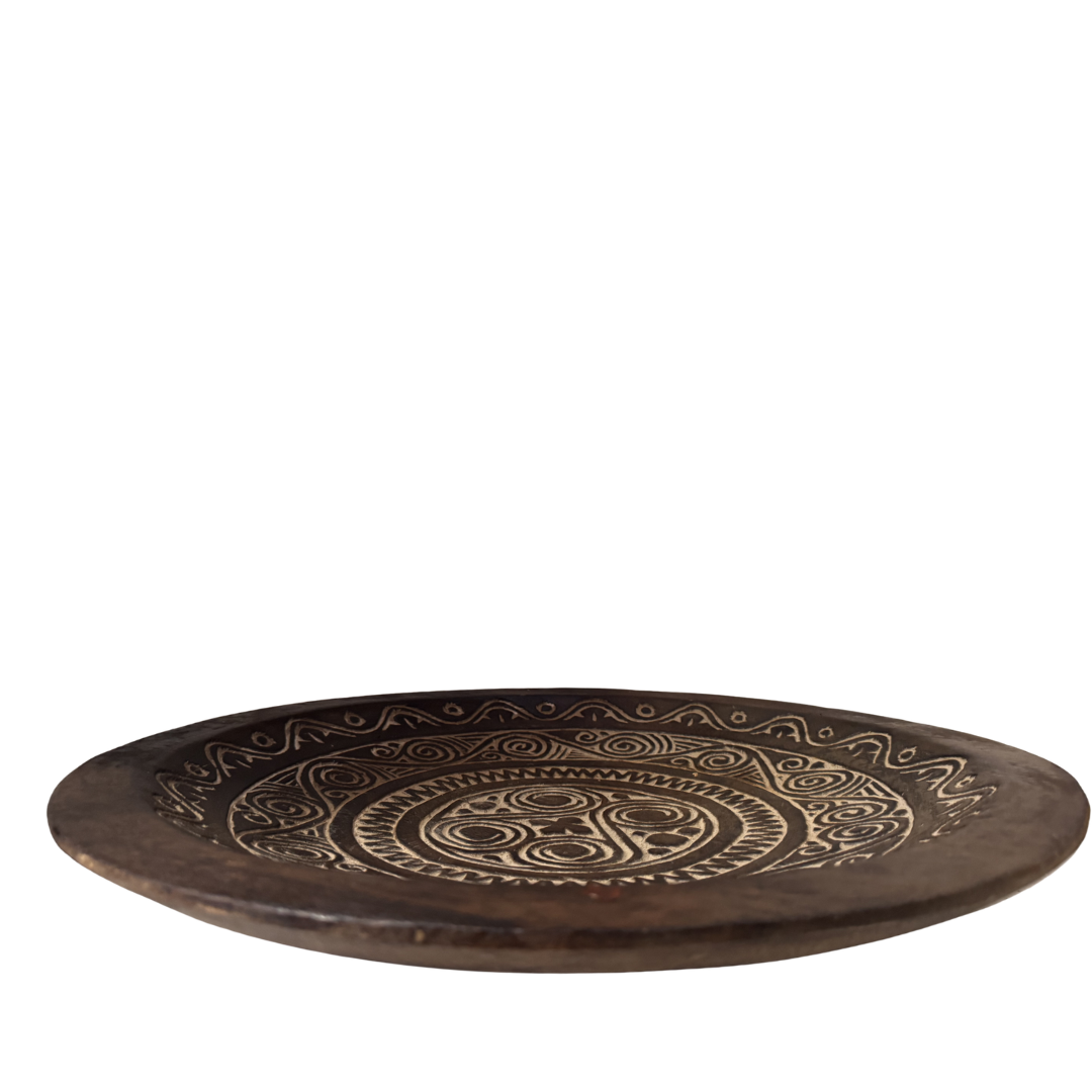 Decorative wooden plate with intricate carvings on a white background