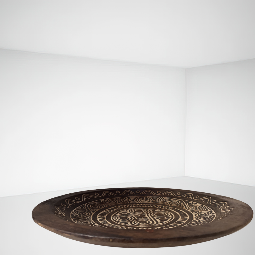 Decorative wooden plate with intricate carvings on a white background