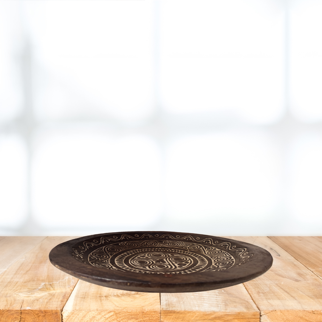 Decorative wooden plate with intricate patterns on a wooden surface.