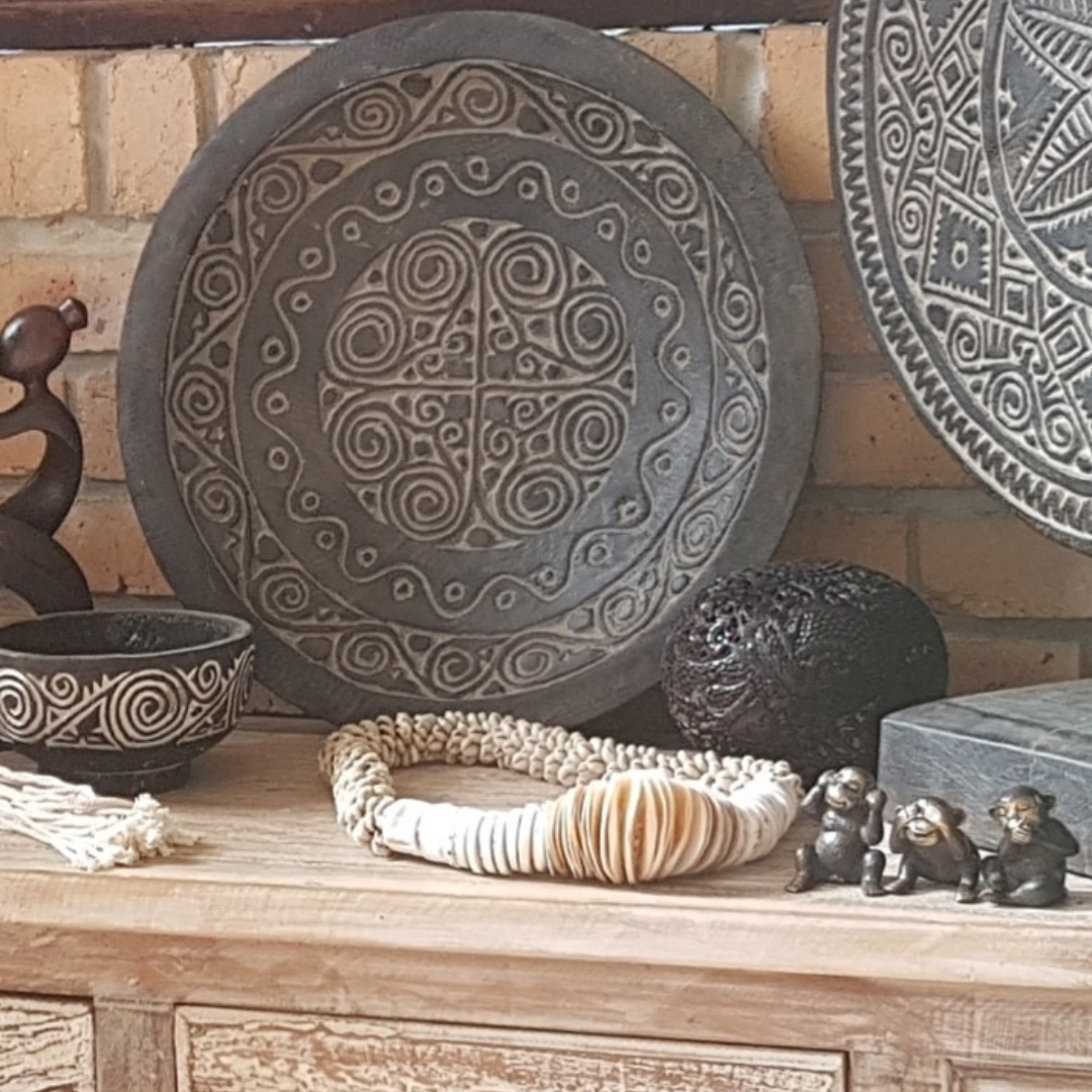 Decorative items including a large round bowl with intricate patterns, a bowl, and small sculptures on a wooden surface.