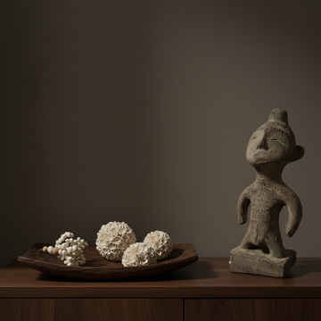 Decorative items including a stone sculpture, a wooden tray with spherical objects, and a dark background.