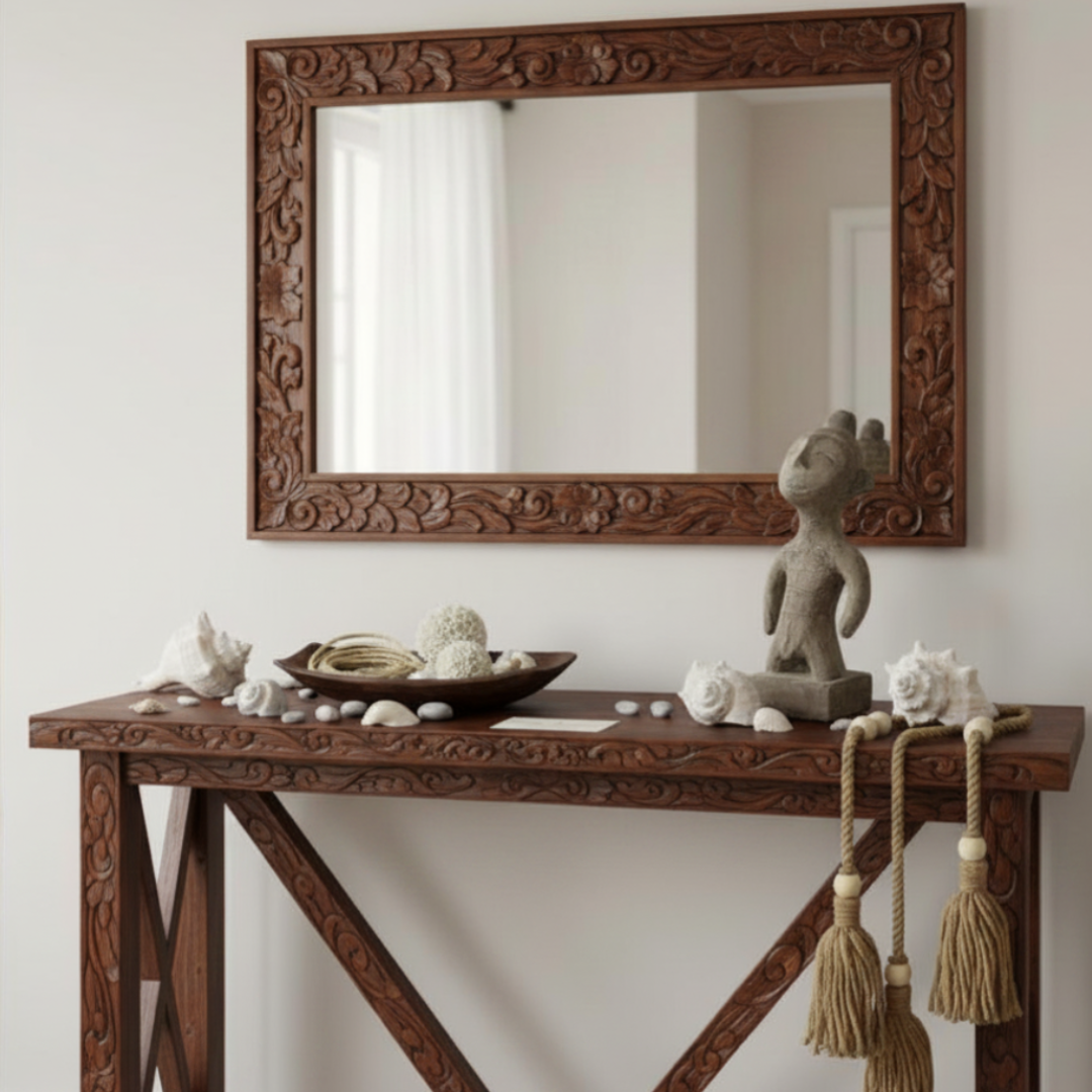 Decorative wooden console table with mirror and decorative items against a white wall