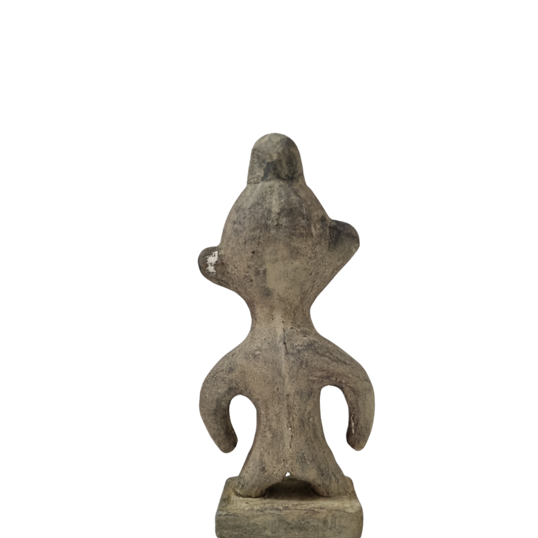 Tribal stone statue inspired by ancient Sulawesi figures displayed on white wall back view 