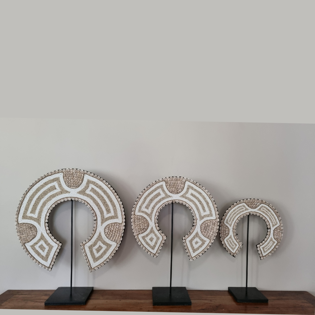 Three decorative wall art pieces on stands against a plain wall.