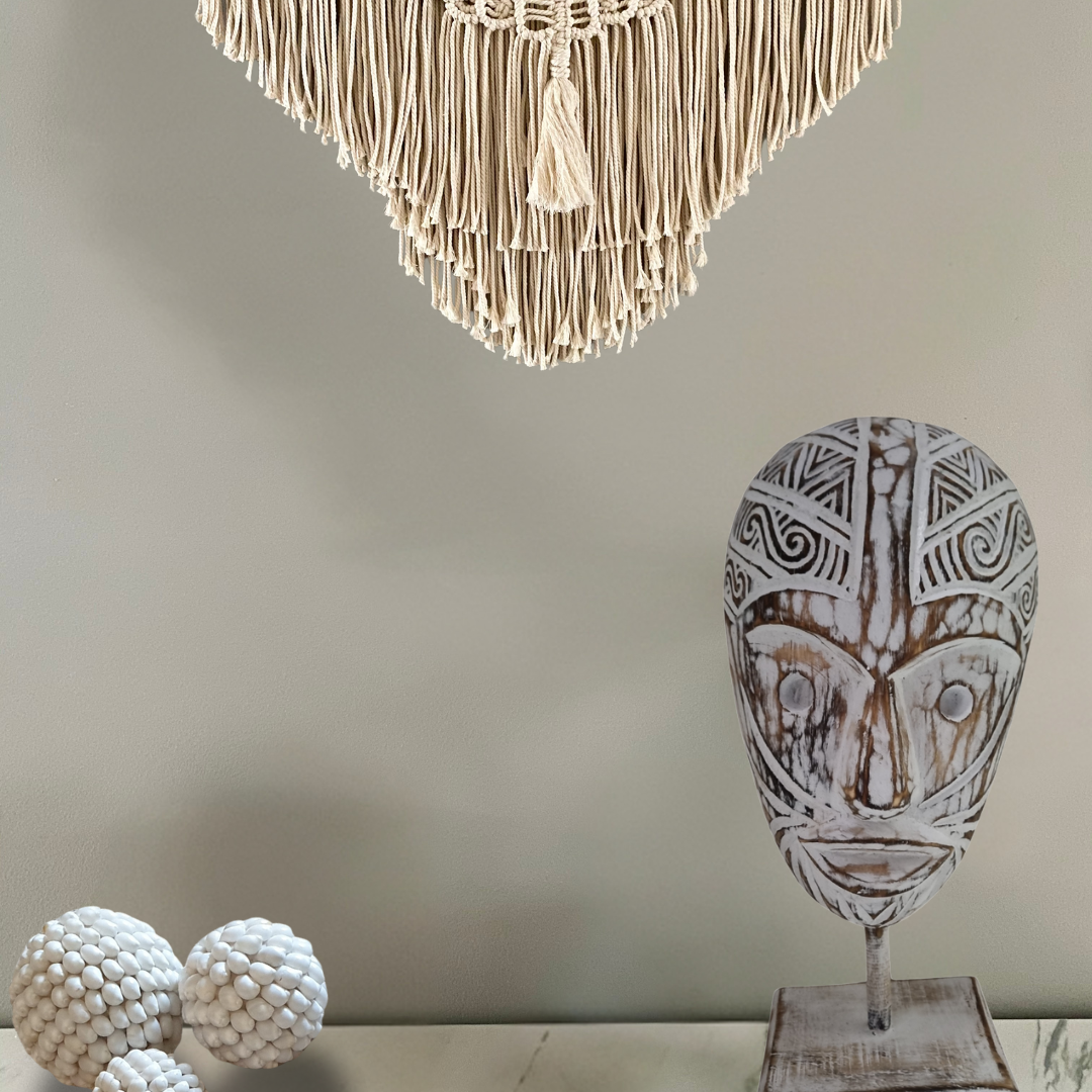 White-wash tribal wooden mask on stand styled in a boho coastal interior with macramé wall hanging | Azure Decor