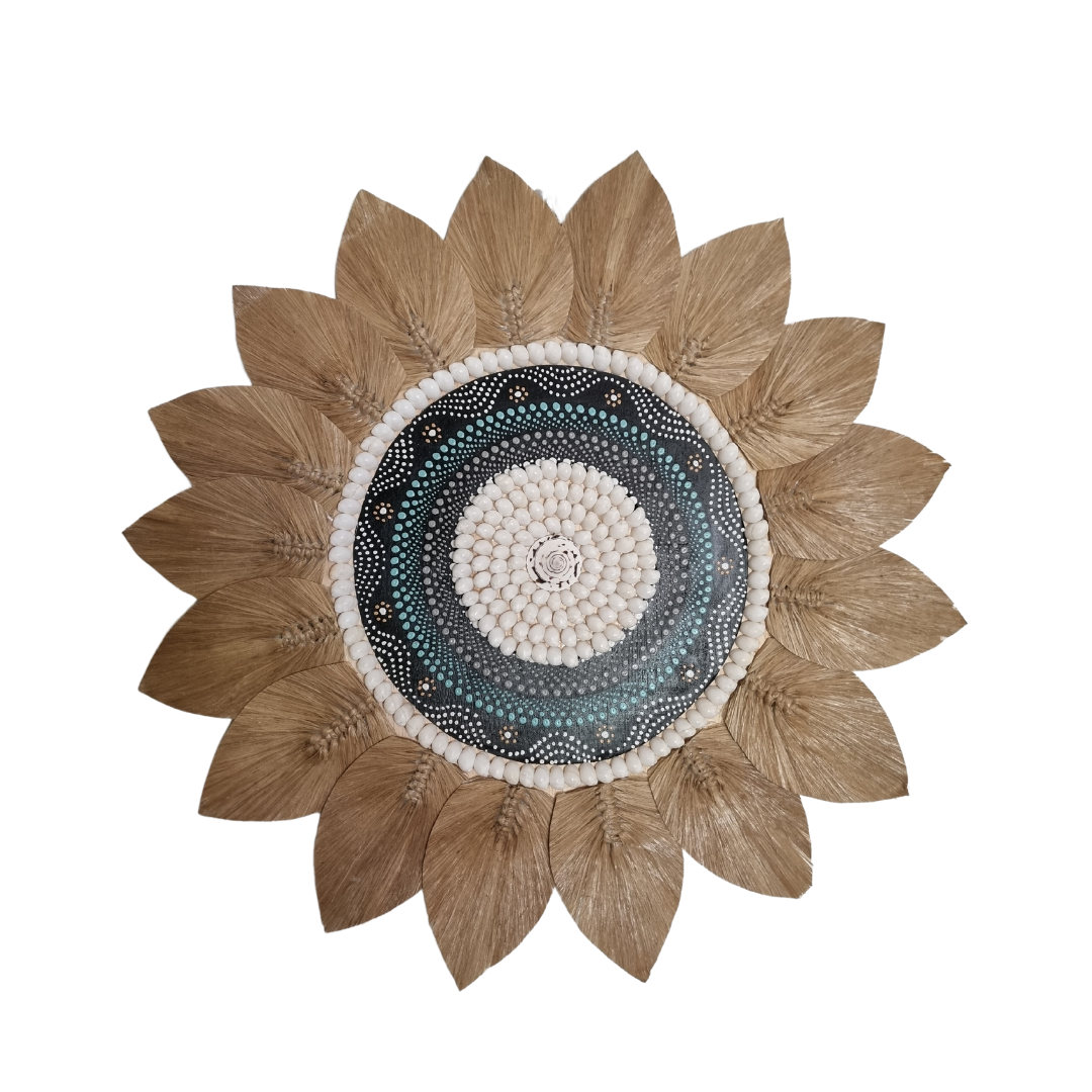 A circular piece of wall art featuring a central painted motif surrounded by seagrass and shells in a tropical style.