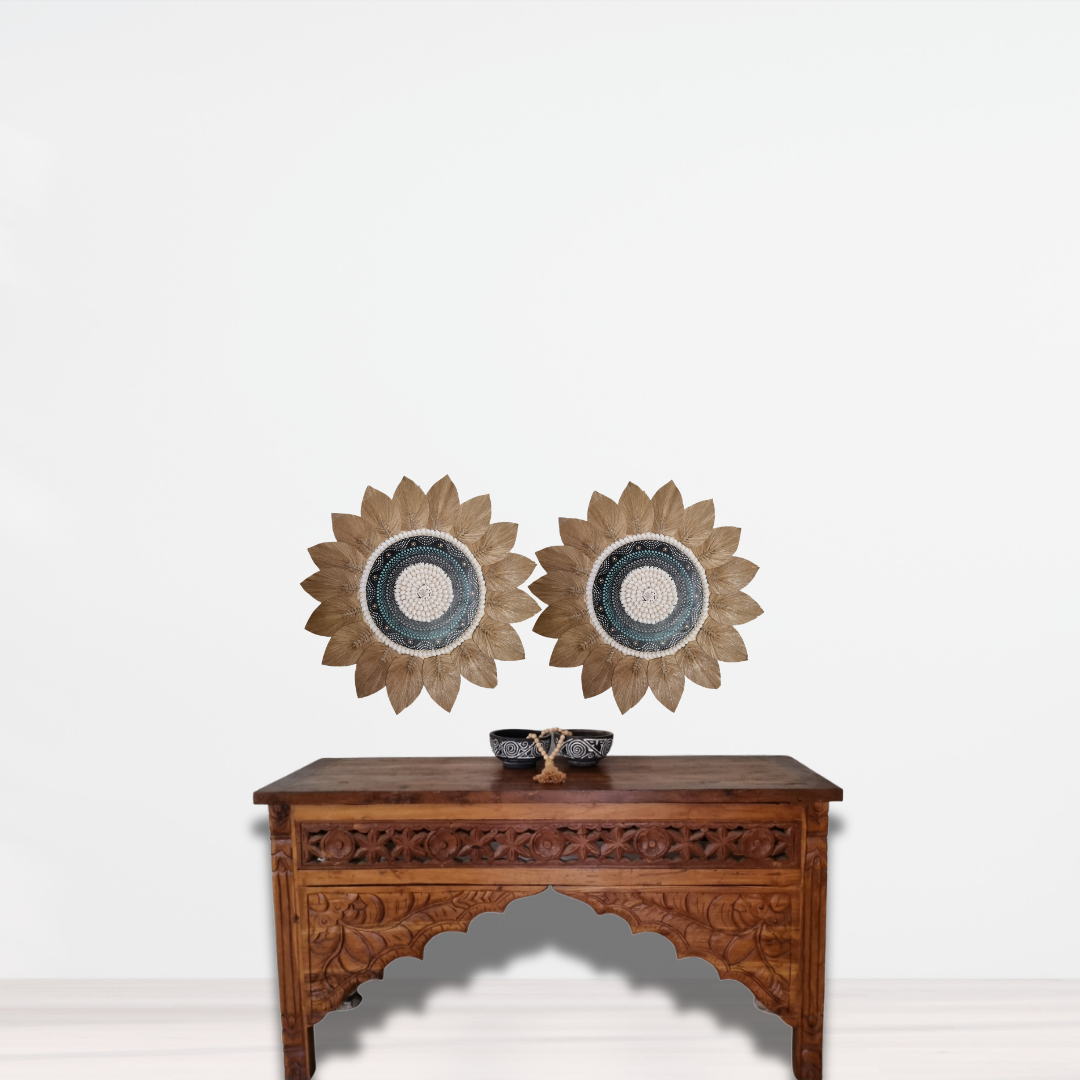 two seagrass and shell artpiece designs in a shape of a flower above a Wooden table with decorative items on a white background