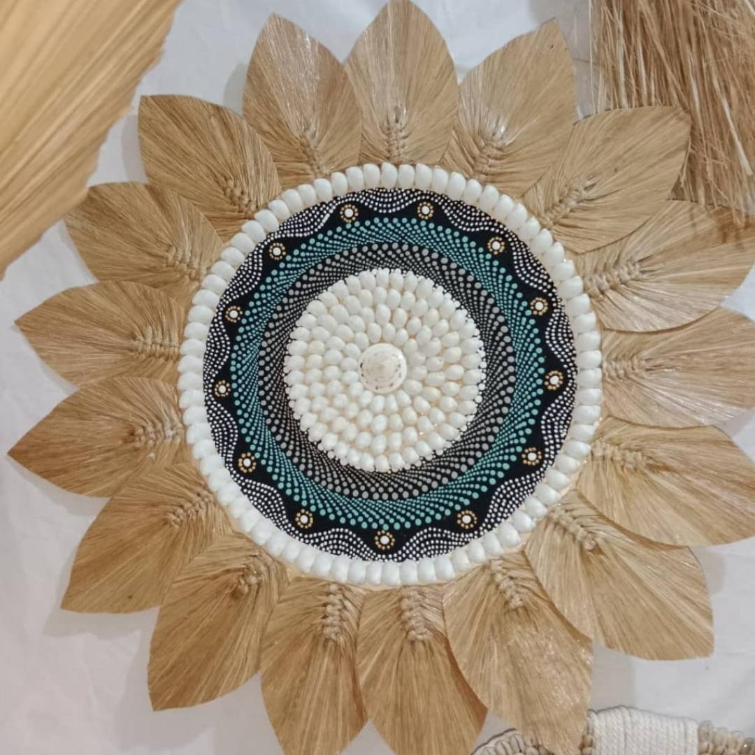 Tropical seagrass and shell wall art with painted centrepiece displayed on beige wall