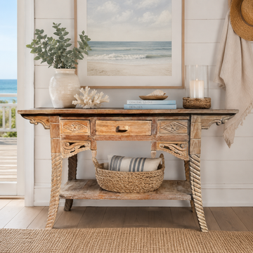 Ubud reclaimed teak console table styled in a coastal entryway with white ceramic vase, coral, candle, woven basket and ocean view artwork above