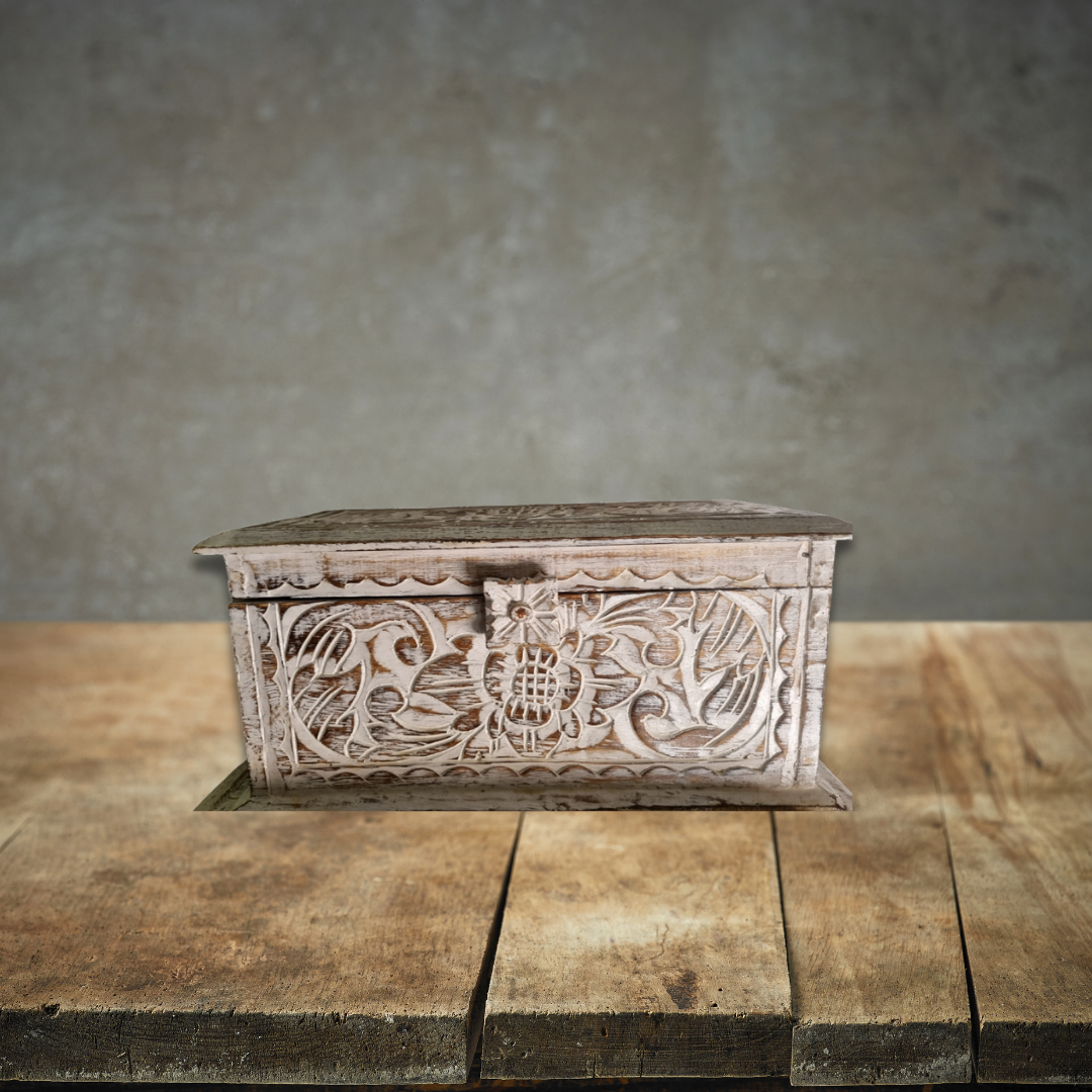 Decorative wooden box with floral carvings on a wooden surface with a gray background