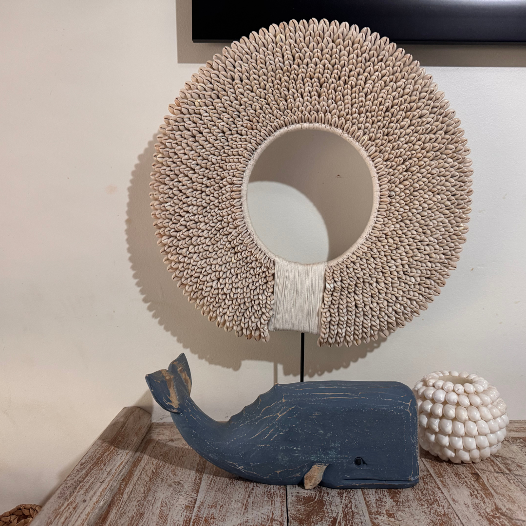 Decorative item with woven circular top and blue whale base on a wooden surface.