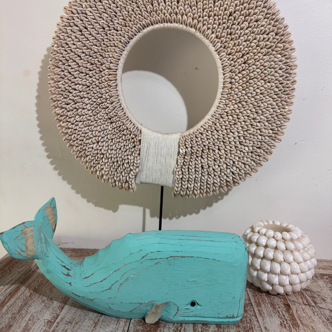 Decorative lamp with woven shade, turquoise whale sculpture, and textured vase on a wooden surface.