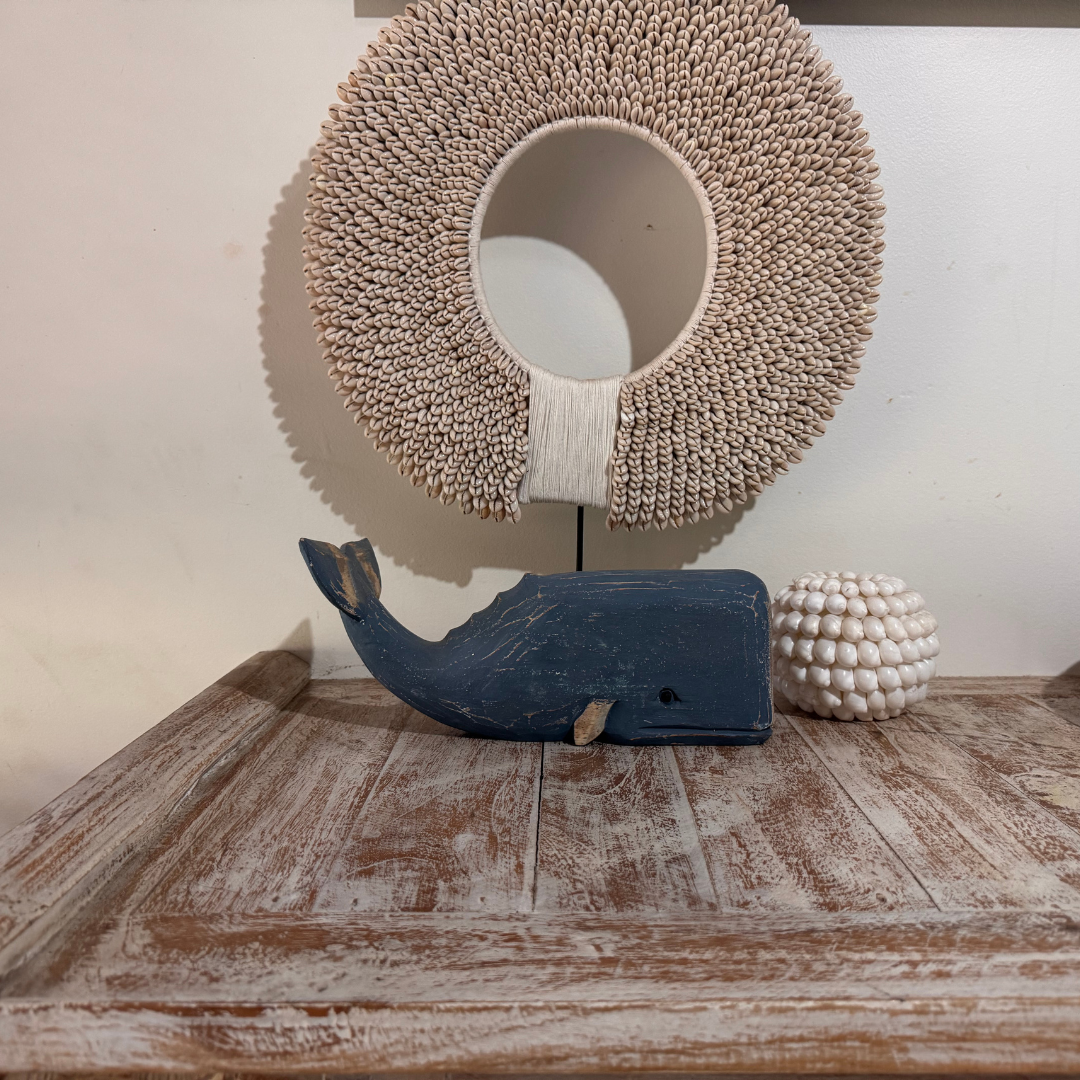 Decorative items including a whale sculpture, woven wall art, and a spherical object on a wooden surface.