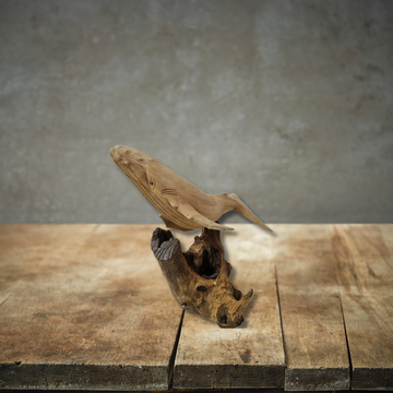 Wooden sculpture of a bird perched on another piece of wood against a gray background