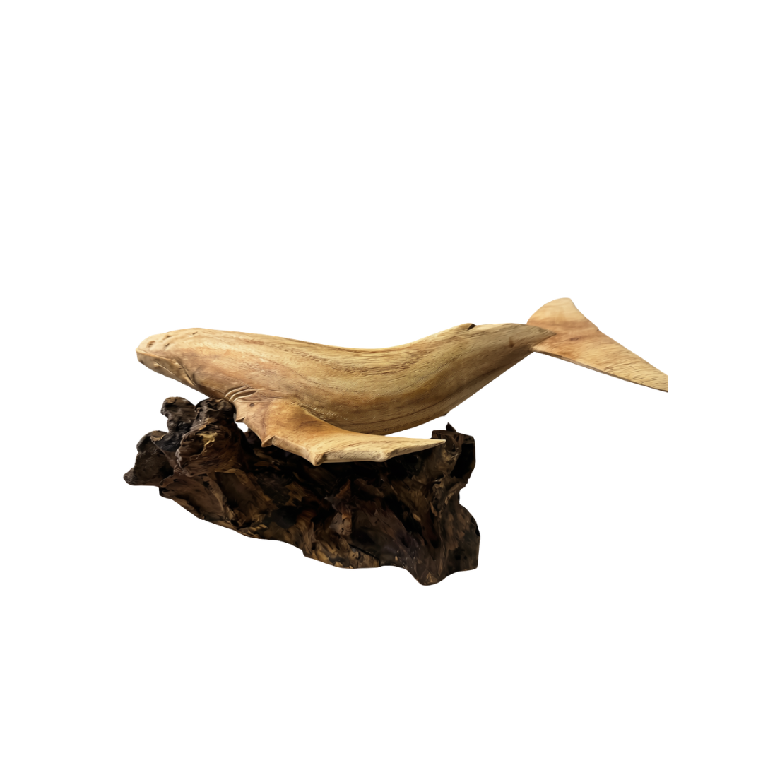 Side profile of a hand-carved wooden humpback whale on a dark driftwood base showing the full body length, natural timber grain, and carved tail flukes