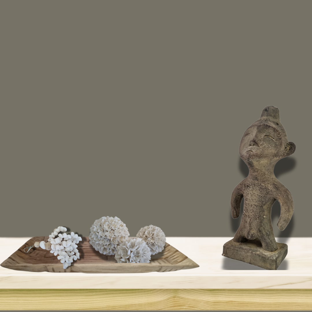 White shell tassel and decorative shell balls styled on a wooden tray beside a rustic carved figurine on a timber shelf