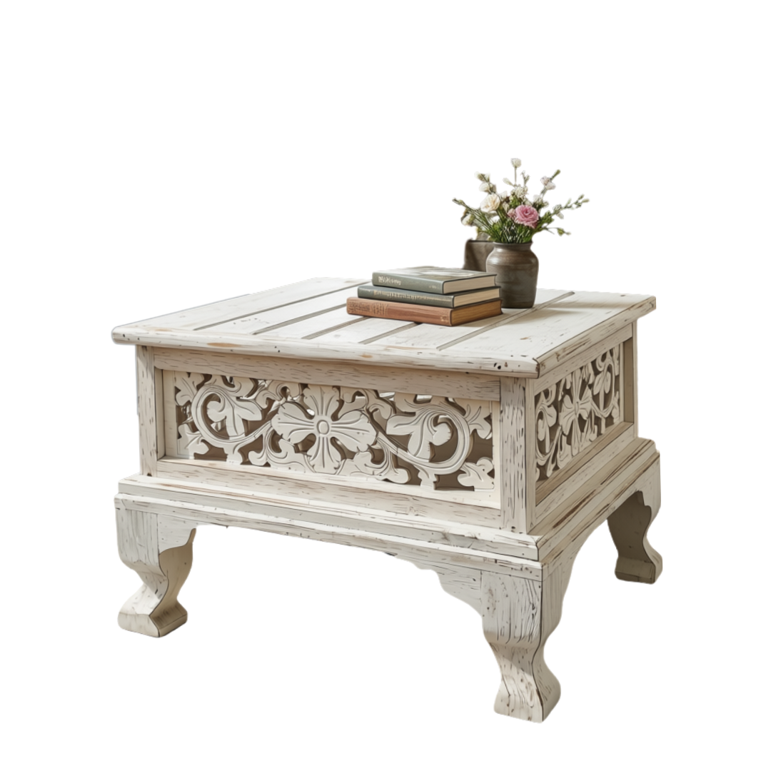 Distressed white wooden table with ornate scrollwork panels, styled with stacked books and a small floral vase