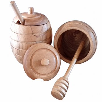 Wooden honey pot with dipper, featuring a beehive-shaped body and fitted lid on a white background