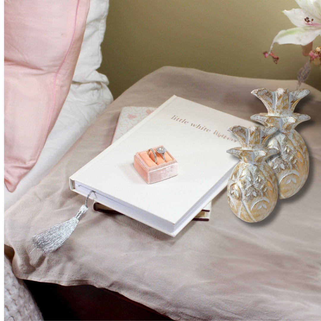 Open book with a ring box on a bed next to decorative vases