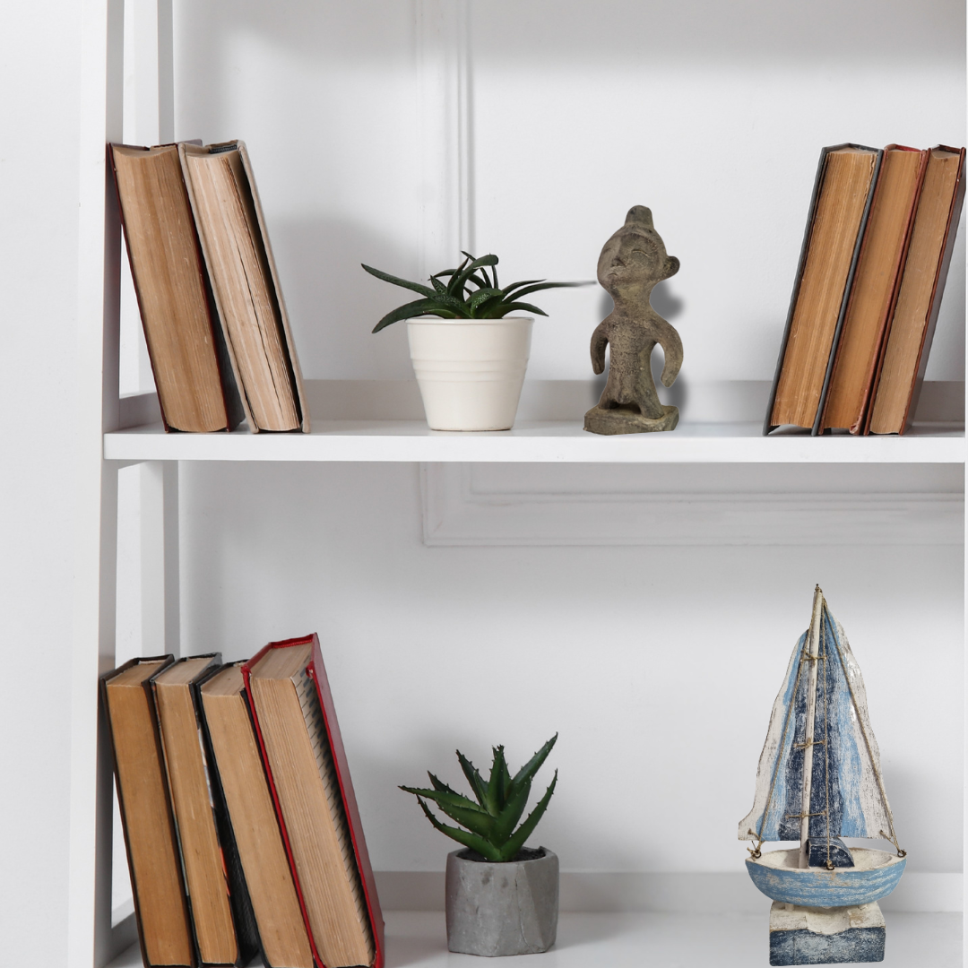 White bookshelf with books, a plant, and decorative items against a white wall.