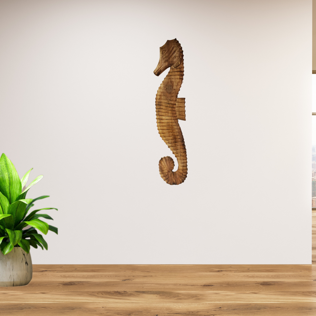 Wooden seahorse wall decor on a plain wall with a plant on a wooden surface.