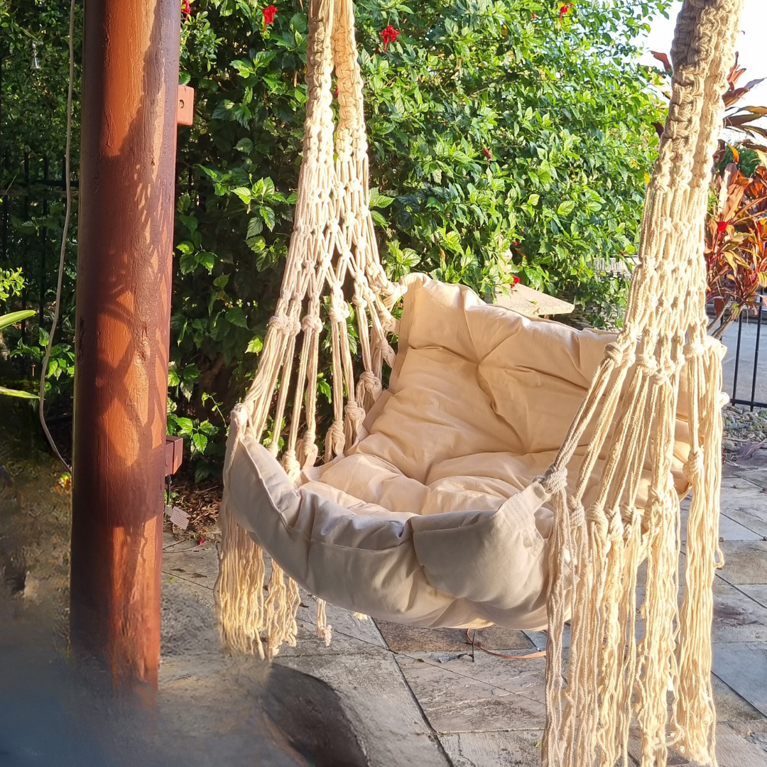 Beige macrame adults chair hanging in a garden 