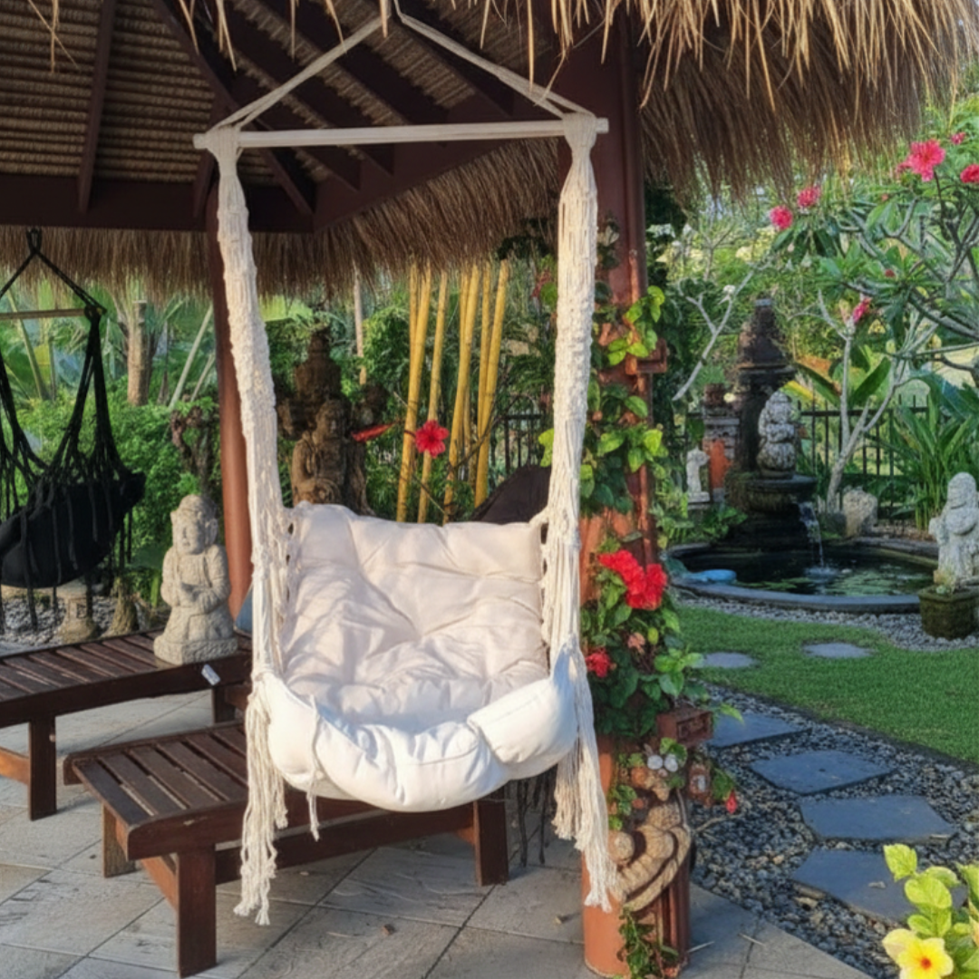 Hammock chair  hanging from a bali hut with a lash garden behind